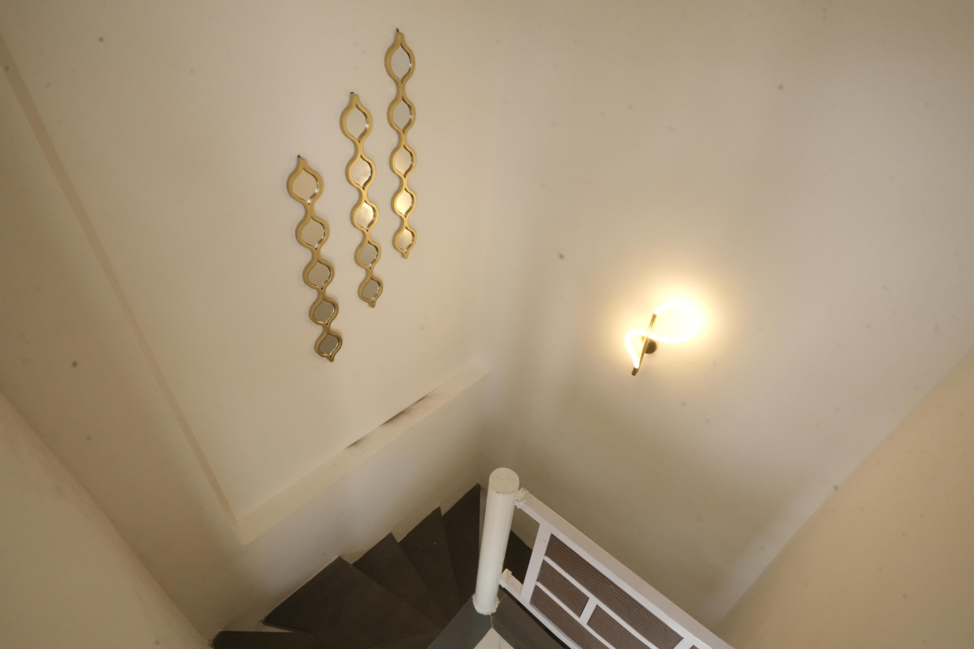 Stairwell with gold accent mirrors and sculptural light