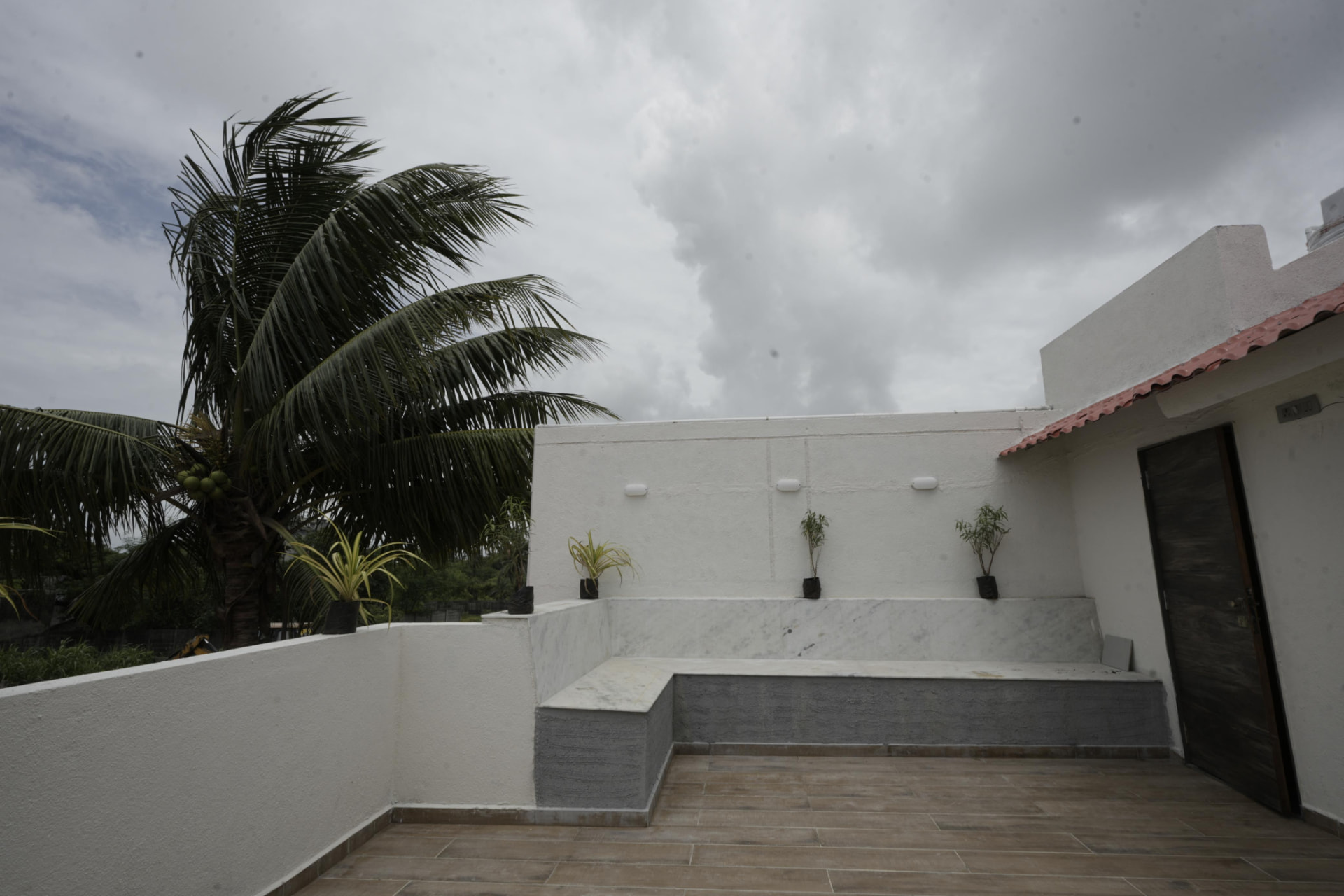 Open-air rooftop terrace with marble seating and palms